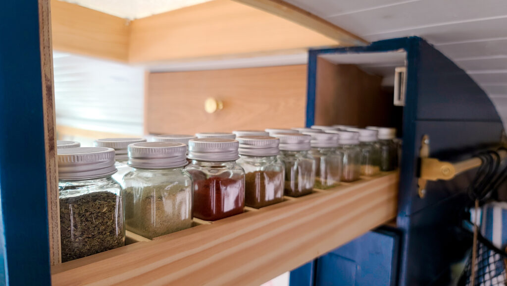 spice containers organized in a skoolie kitchen cabinet